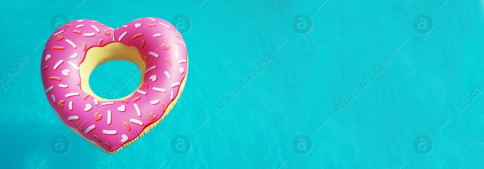 Image of Heart shaped inflatable ring floating in swimming pool on sunny day, above view with space for text. Banner design