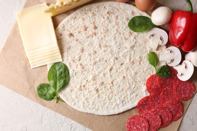 Pizza base and products on light textured table, top view