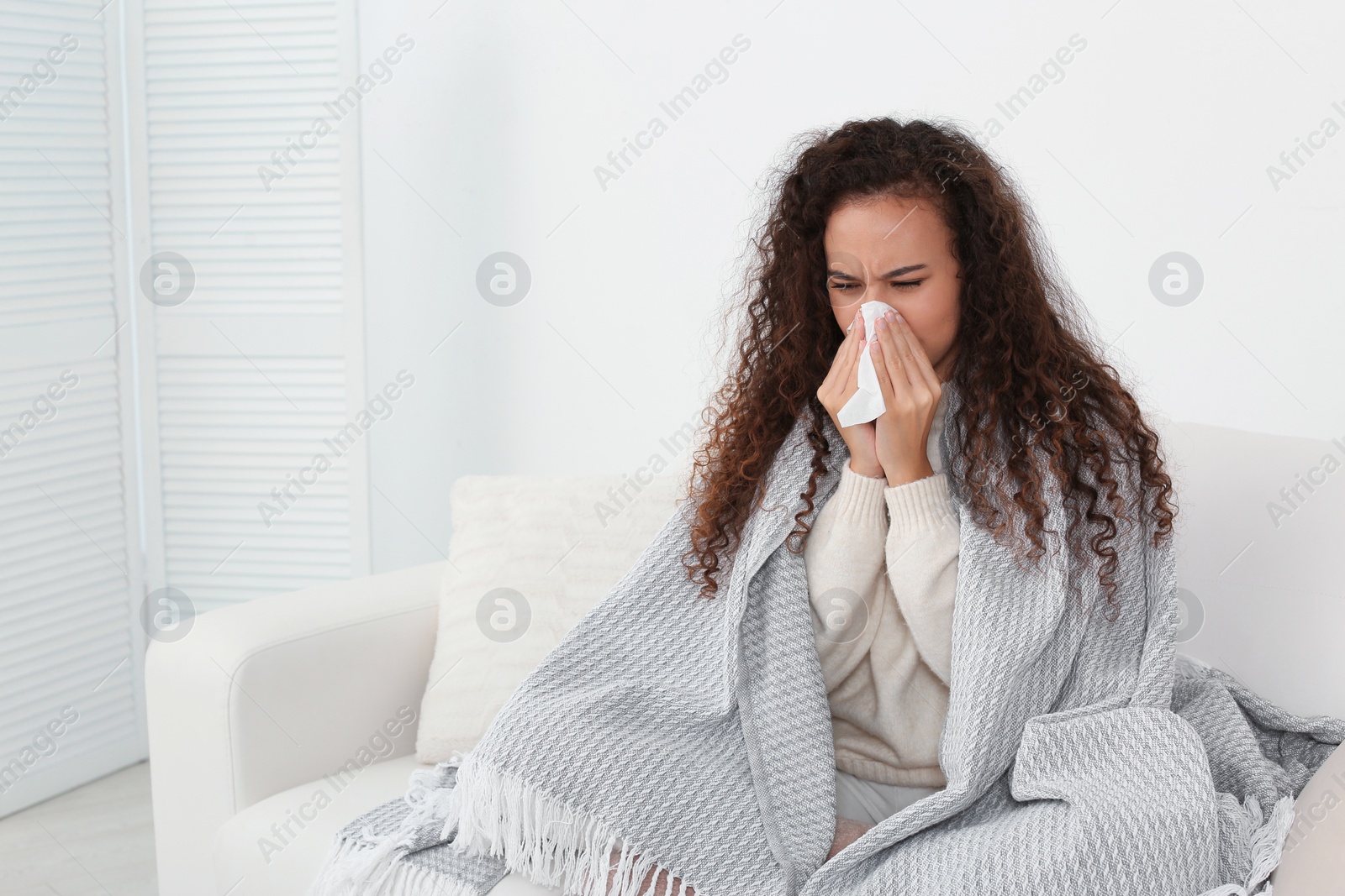 Photo of Sick African American woman with tissue at home, space for text