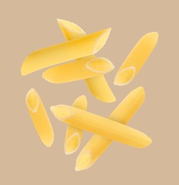 Raw penne pasta flying on beige background