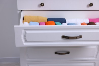 Photo of Open drawer with rolled shirts indoors. Organizing clothes