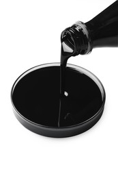 Photo of Pouring black crude oil into Petri dish on white background