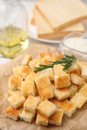 Photo of Delicious crispy croutons with rosemary on table, closeup