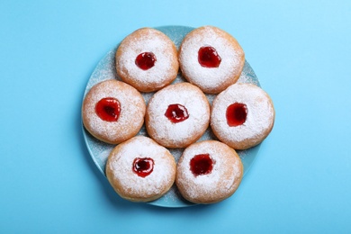 Photo of Hanukkah doughnuts with jelly and sugar powder served on blue background, top view