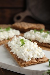 Photo of Crispy crackers with cottage cheese and microgreens on board, closeup