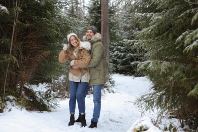 Photo of Couple in conifer forest on snowy day. Winter vacation