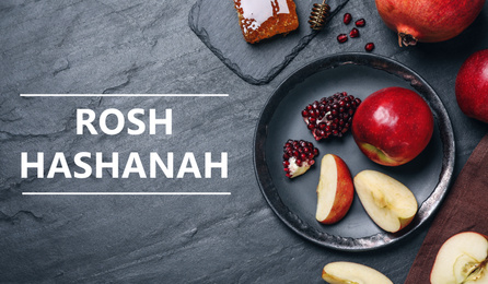 Honey, apples and pomegranates on black table, flat lay. Rosh Hashanah holiday