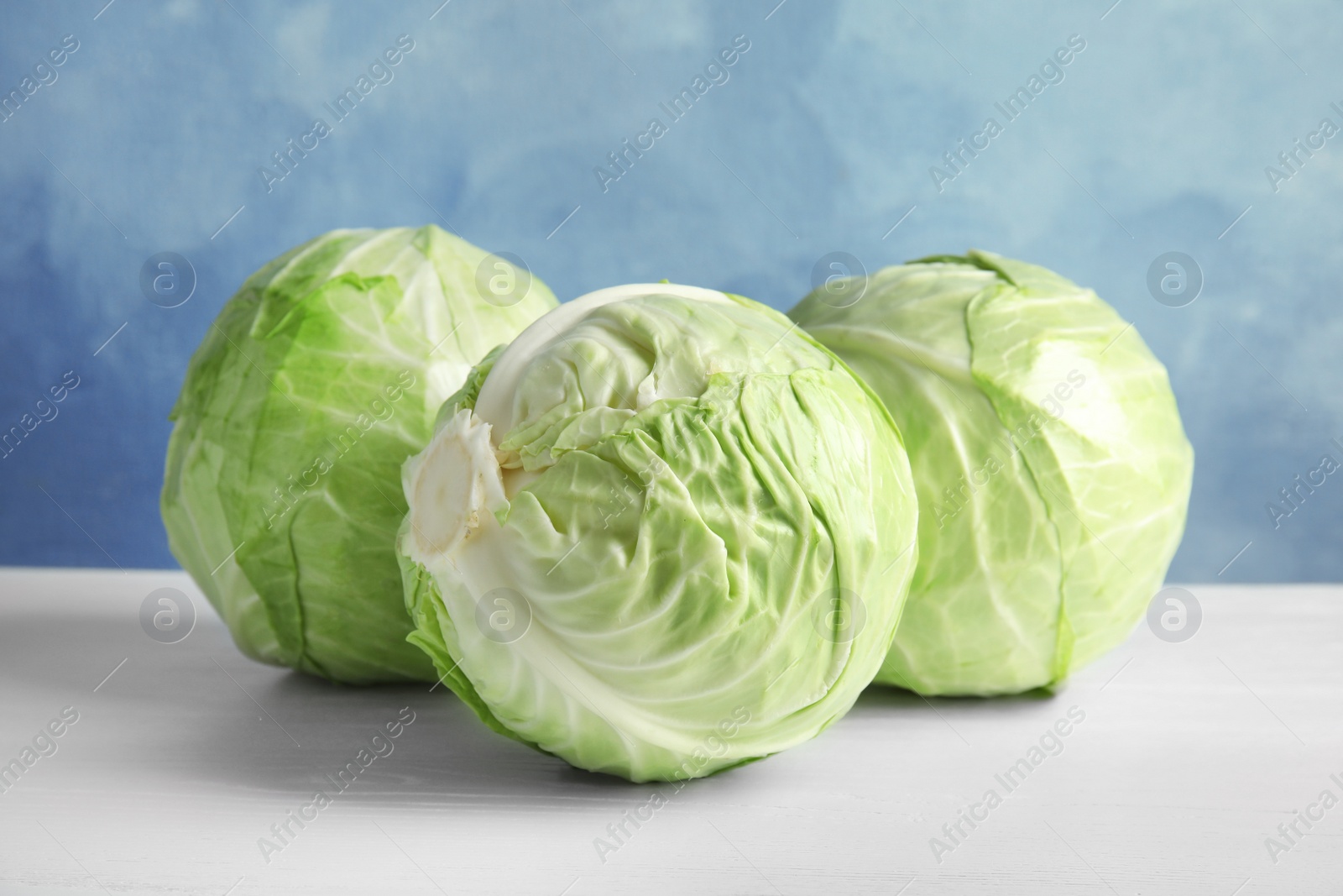 Photo of Whole cabbages on white table. Healthy food