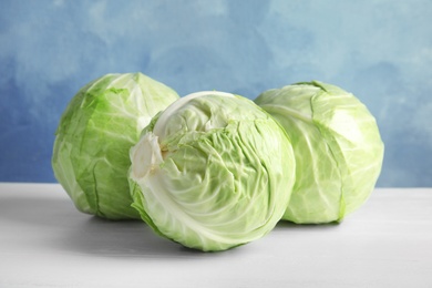 Photo of Whole cabbages on white table. Healthy food