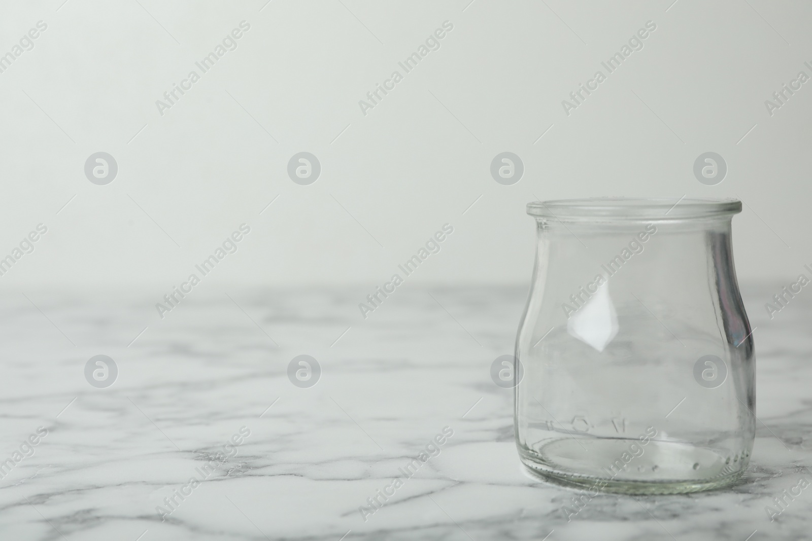 Photo of Empty glass jar on white marble table, space for text