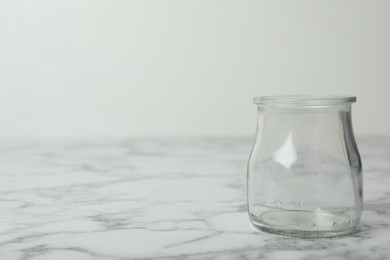 Photo of Empty glass jar on white marble table, space for text