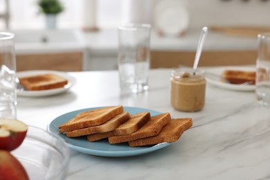 Photo of Breakfast served in kitchen. Crunchy toasts and nut paste on white marble table