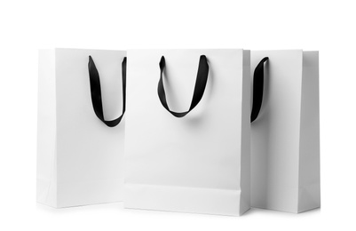 Photo of Paper shopping bags with ribbon handles on white background. Mockup for design