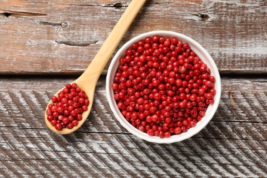 Photo of Aromatic spice. Red pepper in bowl and spoon on wooden table, top view