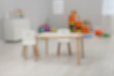 Spacious playroom with furniture and toys in kindergarten, blurred view