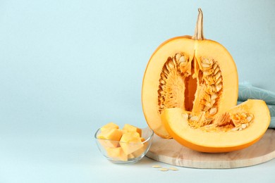 Cut fresh ripe pumpkin on light blue background, space for text