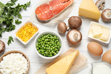 Photo of Flat lay composition with products rich in vitamin D on white wooden table