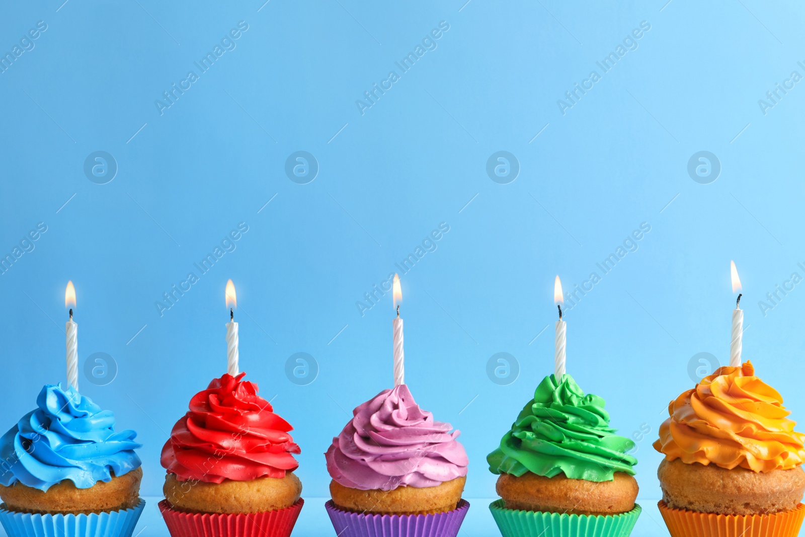 Photo of Delicious birthday cupcakes with candles on color background