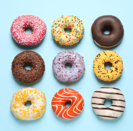Photo of Delicious glazed donuts on light blue background, flat lay