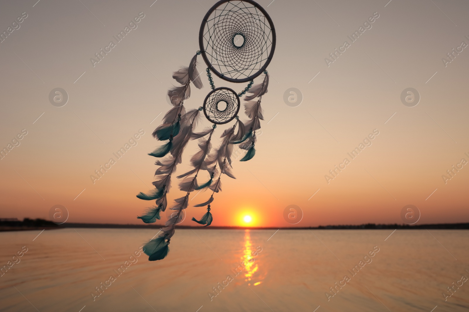 Photo of Beautiful handmade dream catcher near river at sunset. Space for text