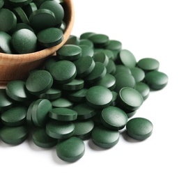 Photo of Wooden bowl with green spirulina pills on white background, closeup