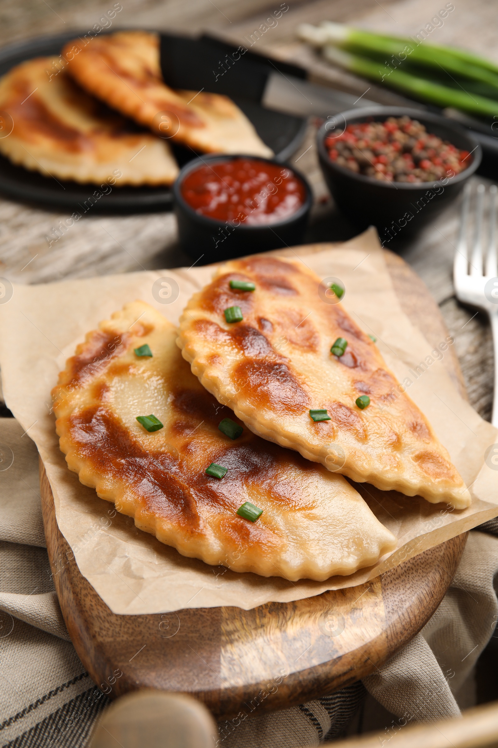 Photo of Delicious fried chebureki served on wooden table