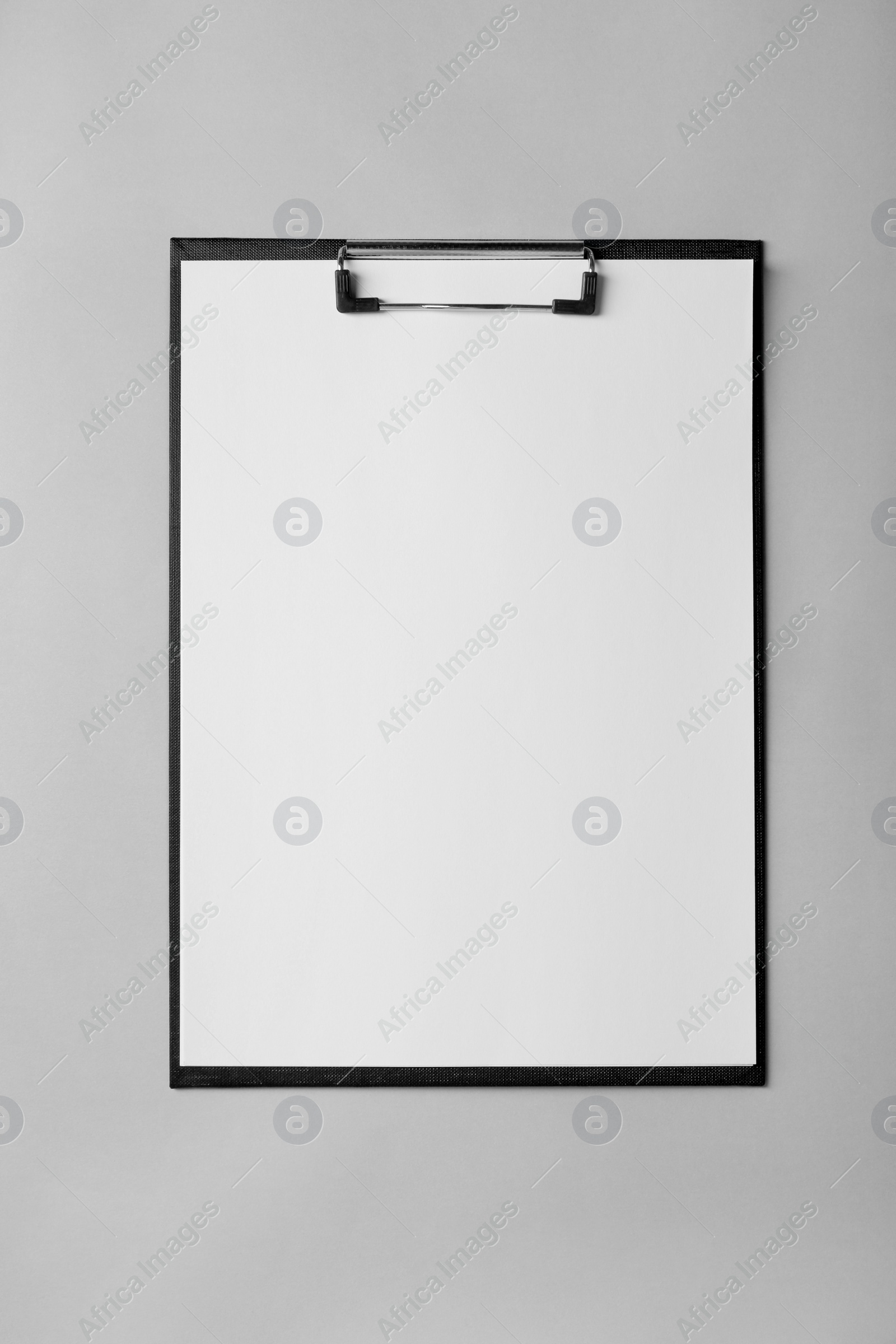 Photo of Black clipboard with sheet of blank paper on light grey background, top view