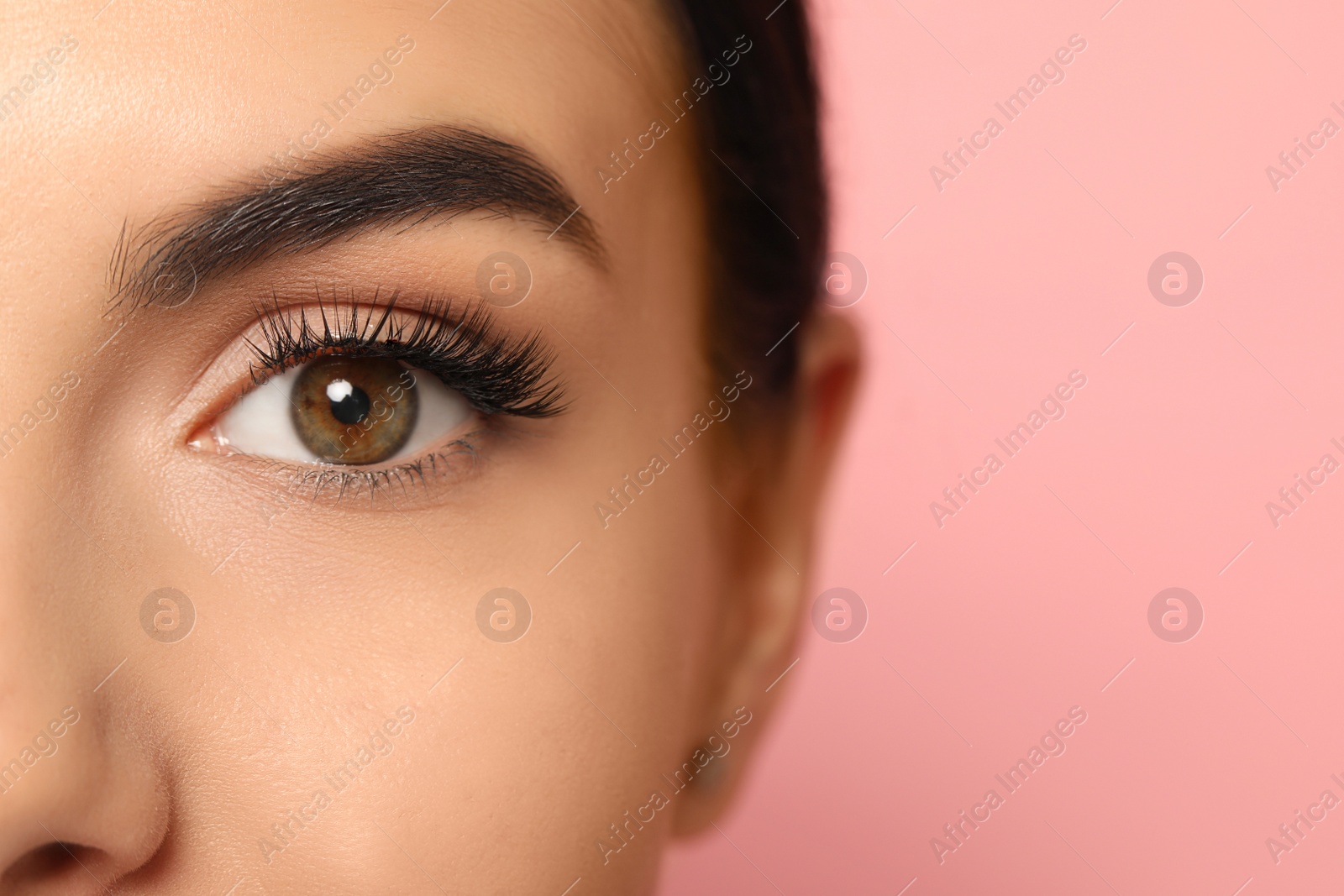 Photo of Beautiful young woman with long eyelashes on pink background, closeup. Space for text