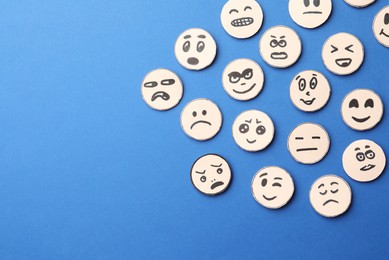 Many faces with different emotions on blue background, flat lay. Space for text