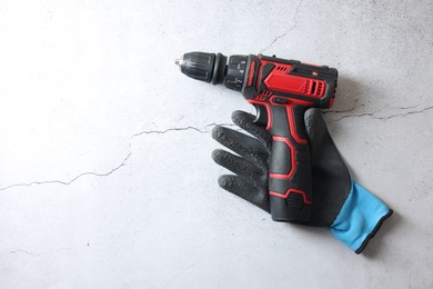 Photo of Electric screwdriver and glove on grey table, top view. Space for text