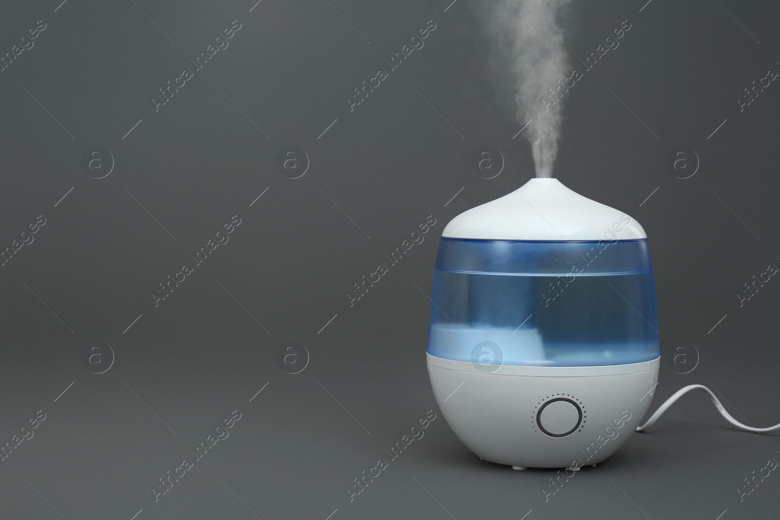 Photo of Modern air humidifier on grey background. Space for text