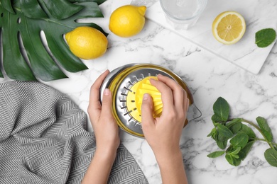 Photo of Woman with squeezer and ingredients for lemonade at marble table, top view