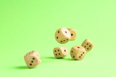 Photo of Many wooden game dices falling on green background