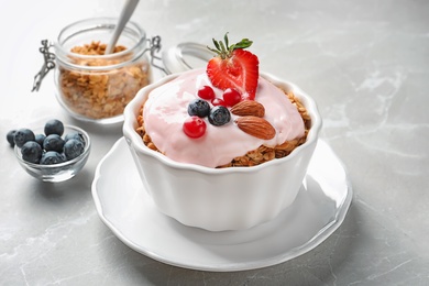 Photo of Bowl with yogurt, berries and granola on table
