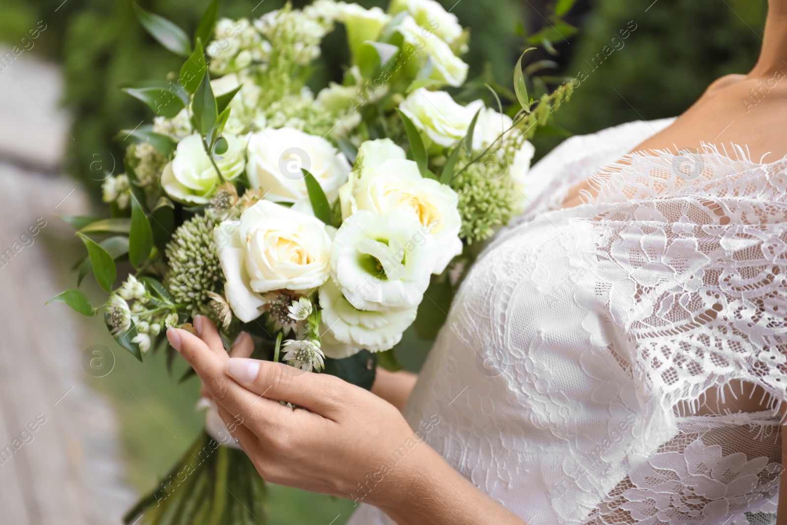 Photo of Bride in beautiful wedding dress with bouquet outdoors, closeup