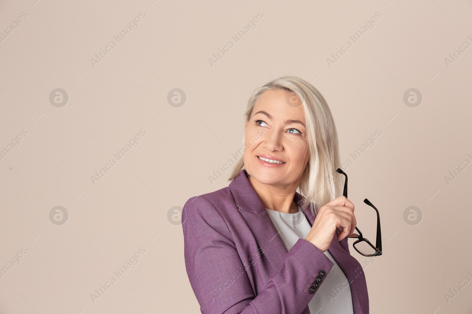 Photo of Portrait of beautiful mature woman with glasses on beige background. Space for text