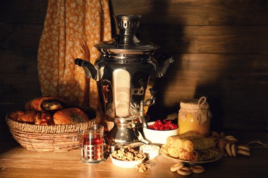 Photo of Traditional Russian samovar and treats on wooden table