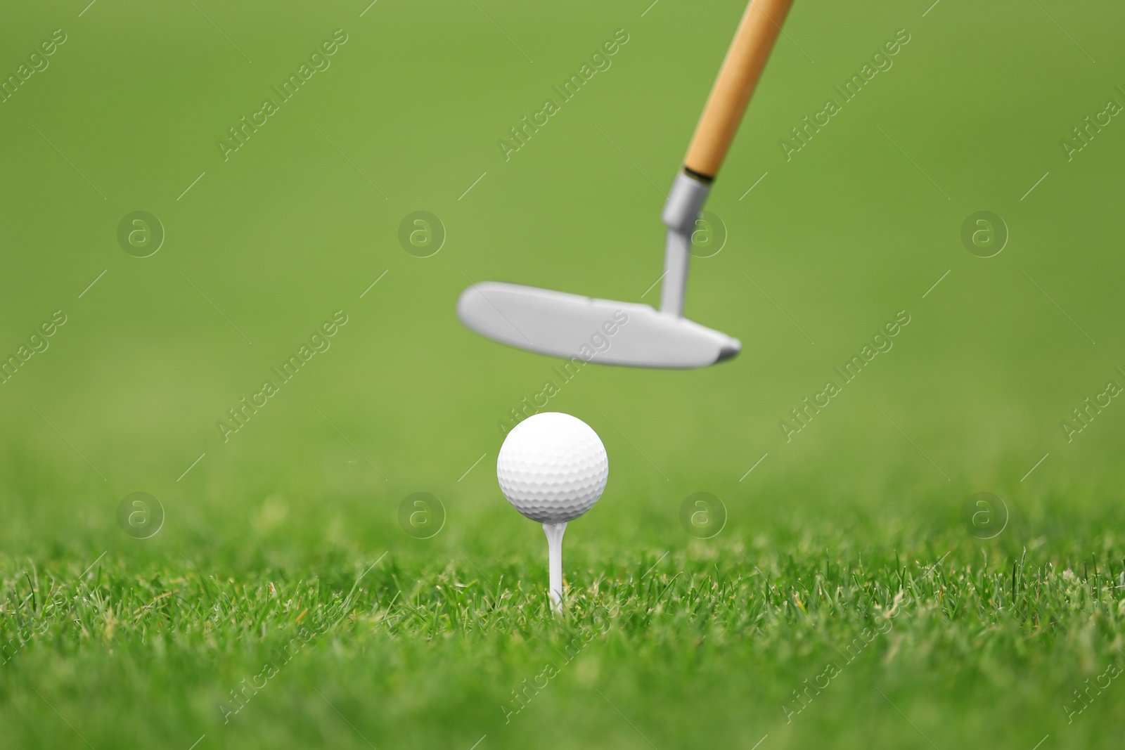 Photo of Hitting golf ball with club on green course