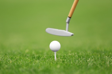 Photo of Hitting golf ball with club on green course