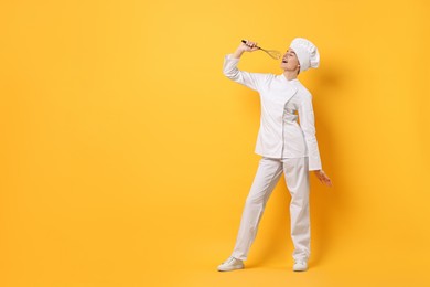 Photo of Professional chef with whisk having fun on yellow background. Space for text