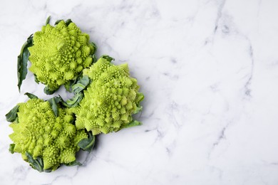 Photo of Fresh Romanesco broccoli on white marble table, flat lay. Space for text
