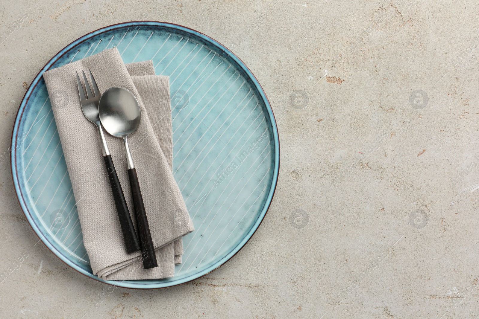 Photo of Stylish setting with cutlery, napkin and plate on light grey table, top view. Space for text