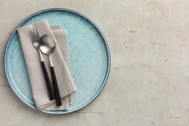 Stylish setting with cutlery, napkin and plate on light grey table, top view. Space for text