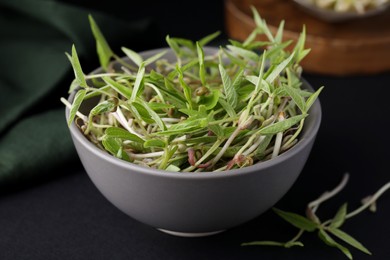 Photo of Mung bean sprouts in bowl on black table, closeup