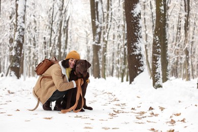 Photo of Woman with adorable Labrador Retriever dog in snowy park, space for text