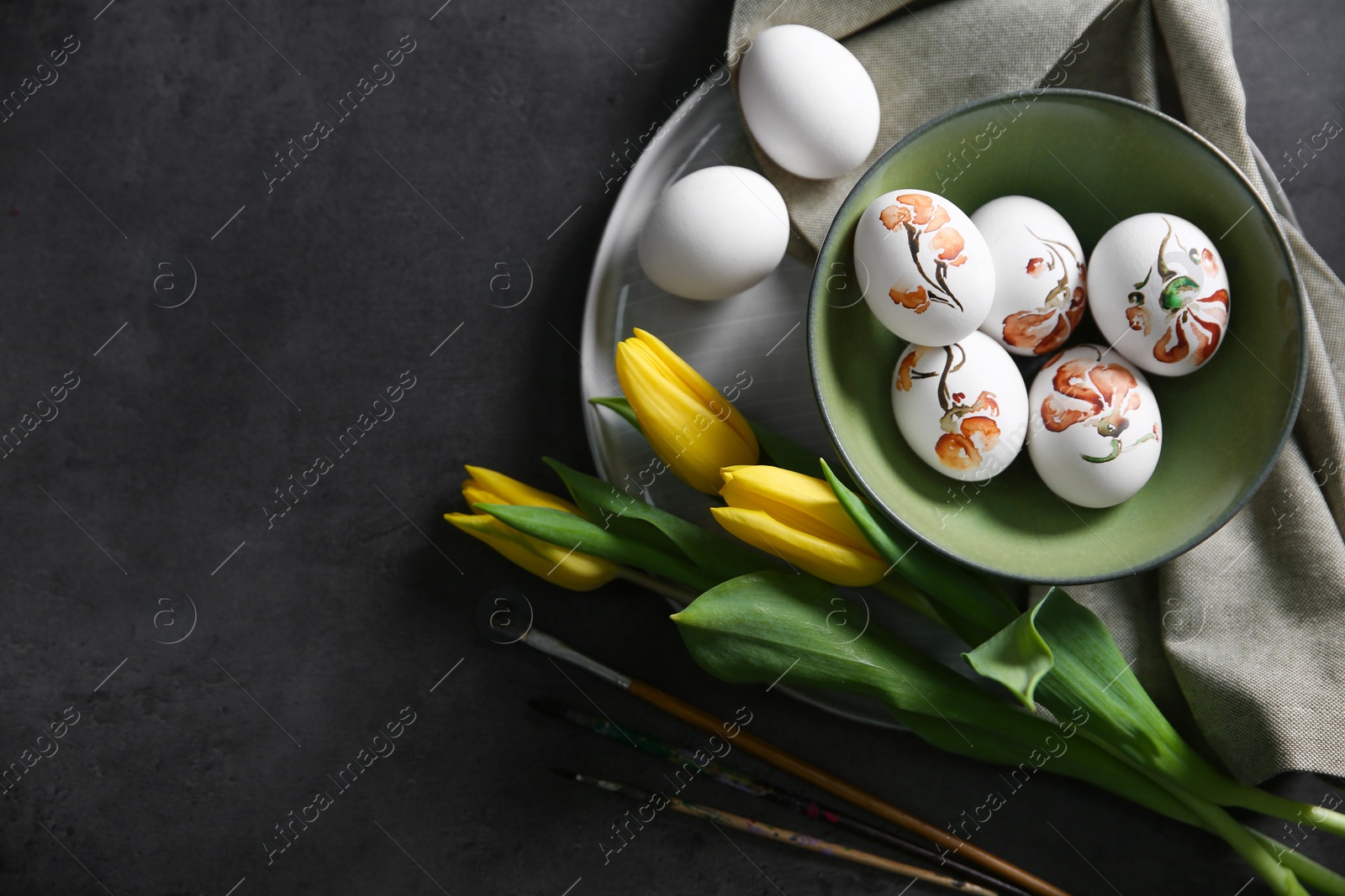 Photo of Flat lay composition with painted Easter eggs on dark table, space for text