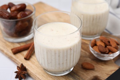 Glass of delicious date smoothie, dried fruits, spices and nuts on table