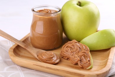 Fresh green apples with peanut butter on table, closeup