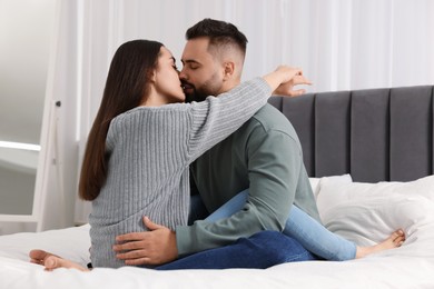 Cute relationship. Affectionate young couple kissing in bedroom