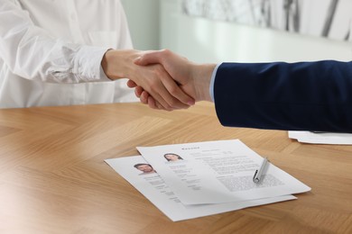 Photo of Human resources manager shaking hands with applicant during job interview in office, closeup